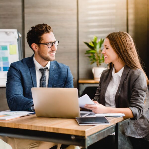 Two people meeting across a desk to plan a business campaign